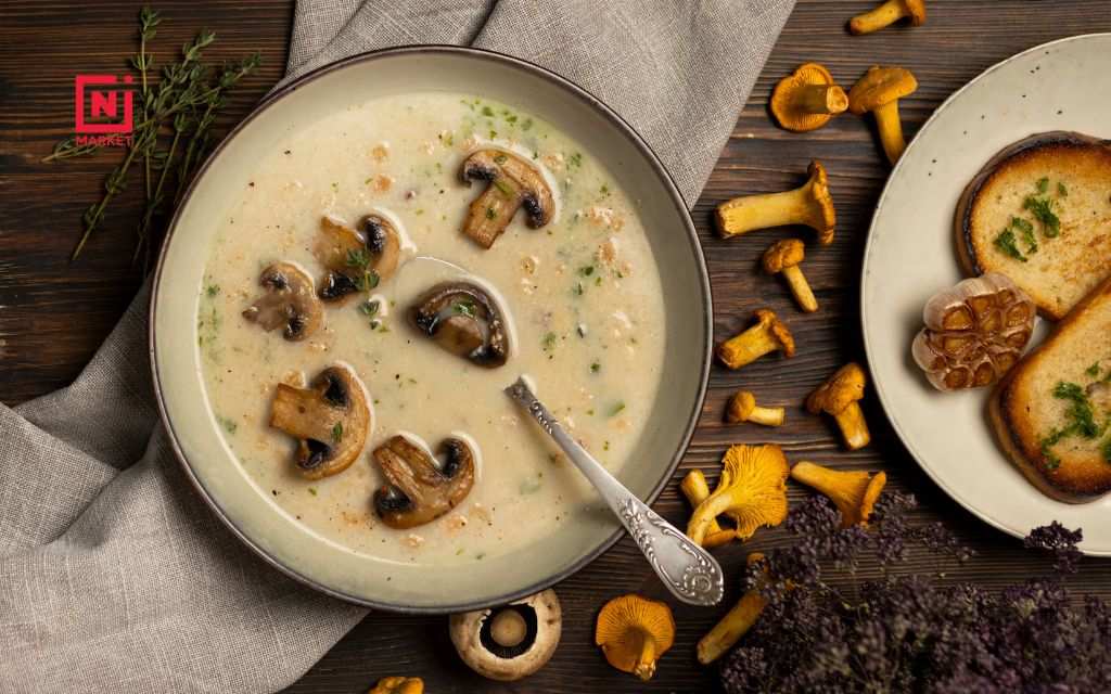 Bowl of oyster mushroom soup served with artisan bread and fresh herbs