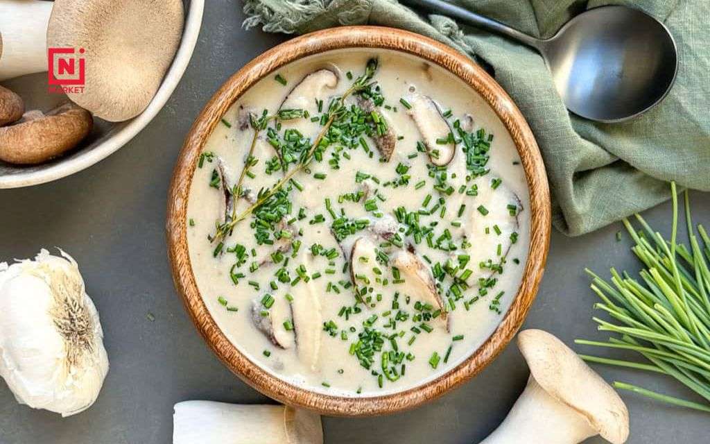 Creamy oyster mushroom soup in white bowl garnished with fresh thyme
